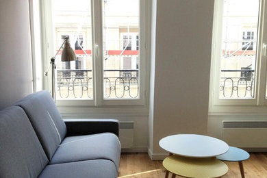 Cette image montre un salon design de taille moyenne et ouvert avec une bibliothèque ou un coin lecture, un mur blanc, parquet clair, aucun téléviseur, un sol marron, aucune cheminée et éclairage.