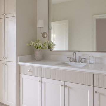 Bathroom vanity with reeded drawer fronts and marble hex tile floor