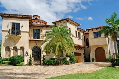 Large mediterranean beige three-story flat roof idea in Miami