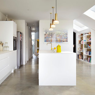 Idéer för små funkis linjära kök med öppen planlösning, med en rustik diskho, släta luckor, vita skåp, bänkskiva i koppar, vitt stänkskydd, glaspanel som stänkskydd, vita vitvaror, betonggolv och en köksö