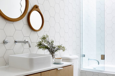 Inspiration for a contemporary 3/4 bathroom in Melbourne with a vessel sink, flat-panel cabinets, light wood cabinets, an alcove tub, a shower/bathtub combo, a two-piece toilet and white tile.