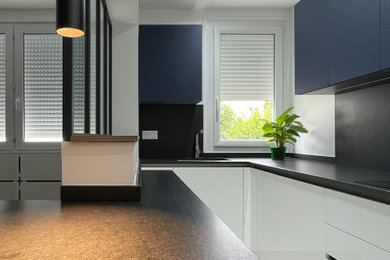パリにある高級な中くらいなコンテンポラリースタイルのおしゃれなキッチン (一体型シンク、インセット扉のキャビネット、白いキャビネット、御影石カウンター、黒いキッチンパネル、御影石のキッチンパネル、パネルと同色の調理設備、セラミックタイルの床、アイランドなし、グレーの床、黒いキッチンカウンター、折り上げ天井) の写真