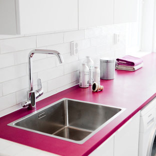 シャビーシック調のおしゃれなランドリールーム (シングルシンク、フラットパネル扉のキャビネット、白いキャビネット、人工大理石カウンター、白い壁、左右配置の洗濯機・乾燥機、ピンクのキッチンカウンター) の写真