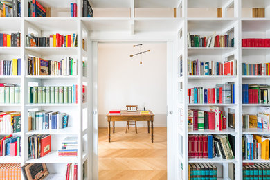 Esempio di uno studio classico con libreria, parquet chiaro, scrivania autoportante, pareti bianche e pavimento beige