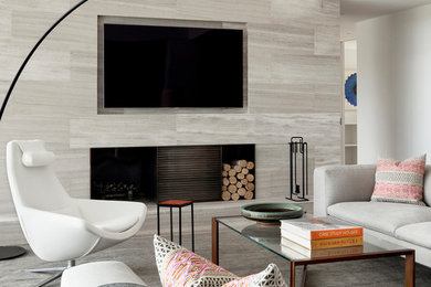 Mid-sized modern loft-style family room in New York with white walls, medium hardwood floors, a standard fireplace, a stone fireplace surround, a wall-mounted tv and grey floor.