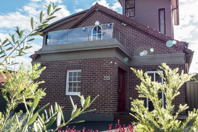Contemporary two-storey brick brown house exterior in Sydney with a gable roof, a tile roof and a red roof.