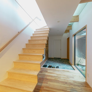 京都のモダンスタイルのおしゃれな玄関 (マルチカラーの壁、茶色いドア、グレーの床) の写真