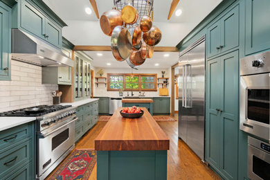 Enclosed kitchen - large farmhouse l-shaped medium tone wood floor, brown floor and exposed beam enclosed kitchen idea in Providence with a farmhouse sink, shaker cabinets, green cabinets, quartzite countertops, white backsplash, ceramic backsplash, stainless steel appliances, two islands and white countertops