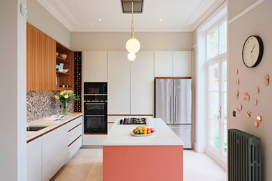 Mid-sized eclectic l-shaped eat-in kitchen in London with an undermount sink, flat-panel cabinets, white cabinets, solid surface benchtops, multi-coloured splashback, mosaic tile splashback, black appliances, light hardwood floors, with island, grey floor and white benchtop.