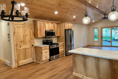 Example of a mid-sized mountain style galley vinyl floor, yellow floor and wood ceiling open concept kitchen design in Minneapolis with an undermount sink, shaker cabinets, light wood cabinets, laminate countertops, stainless steel appliances, a peninsula and white countertops