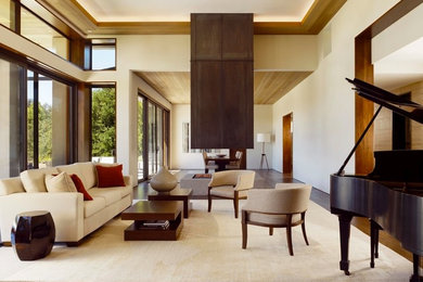 This is an example of a modern open concept living room in San Francisco with a music area, beige walls, medium hardwood floors and a two-sided fireplace.