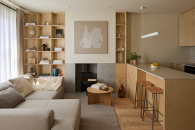 Inspiration for a contemporary cream and black living room in London with beige walls, light hardwood flooring, a wood burning stove, a tiled fireplace surround and beige floors.