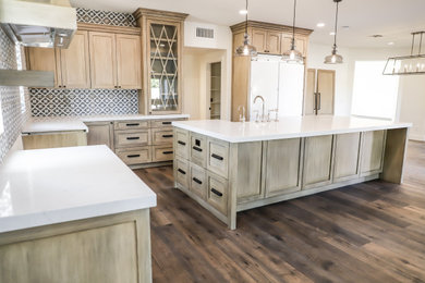 Example of a mid-sized classic kitchen design in Phoenix with light wood cabinets, ceramic backsplash, paneled appliances, an island and white countertops