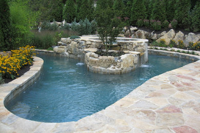This is an example of an expansive transitional backyard custom-shaped natural pool in New York with a water feature and natural stone pavers.