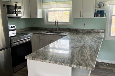 Example of a mid-sized beach style u-shaped dark wood floor and brown floor eat-in kitchen design in Bridgeport with an undermount sink, shaker cabinets, white cabinets, marble countertops, blue backsplash, stainless steel appliances, a peninsula and blue countertops