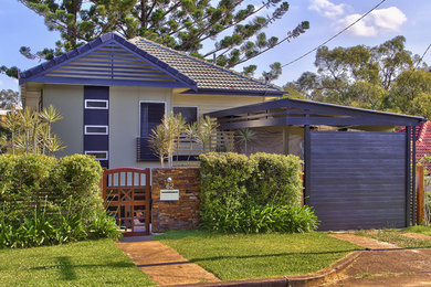 This is an example of a mid-sized tropical two-storey grey exterior in Brisbane with concrete fiberboard siding and a gable roof.