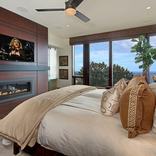 Mittelgroßes Modernes Hauptschlafzimmer mit Gaskamin, weißer Wandfarbe, dunklem Holzboden, Kaminumrandung aus Holz und braunem Boden in Orange County