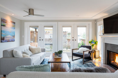 Example of a mid-sized transitional open concept medium tone wood floor and brown floor family room design in Vancouver with gray walls, a standard fireplace, a tile fireplace and a wall-mounted tv