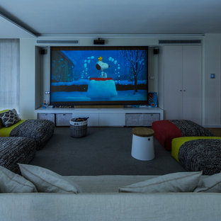 Inspiration pour une grande salle de cinéma fermée avec un mur blanc, un sol en bois clair et un téléviseur fixé au mur.