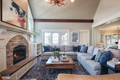 Inspiration for a large transitional dark wood floor and vaulted ceiling living room remodel in Denver with a standard fireplace, a stacked stone fireplace and a wall-mounted tv