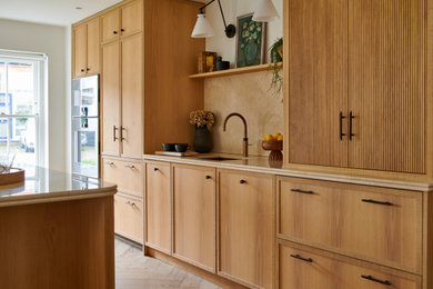 Design ideas for a medium sized rustic cream and black single-wall open plan kitchen in Sussex with a submerged sink, shaker cabinets, medium wood cabinets, marble worktops, beige splashback, marble splashback, black appliances, light hardwood flooring, an island, brown floors and beige worktops.