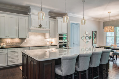 Inspiration for a mid-sized transitional l-shaped eat-in kitchen in Charlotte with an undermount sink, shaker cabinets, dark wood cabinets, marble benchtops, grey splashback, ceramic splashback, stainless steel appliances, dark hardwood floors, with island and brown floor.