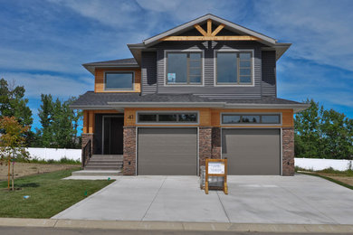 This is an example of a mid-sized arts and crafts two-storey multi-coloured house exterior in Calgary with mixed siding, a shingle roof and a hip roof.