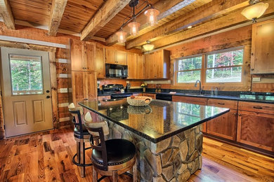 Inspiration for a rustic l-shaped medium tone wood floor open concept kitchen remodel in Columbus with shaker cabinets, medium tone wood cabinets, granite countertops, black appliances and an island