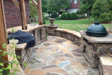 Inspiration for a large timeless backyard stone patio kitchen remodel in Charlotte with a pergola