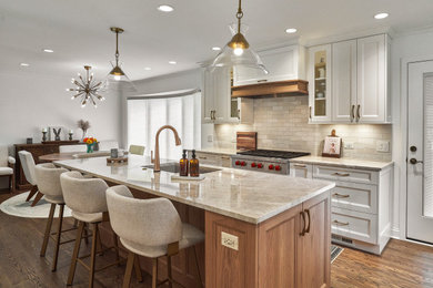 Inspiration for a large timeless u-shaped medium tone wood floor and brown floor open concept kitchen remodel in Chicago with an undermount sink, shaker cabinets, medium tone wood cabinets, quartzite countertops, beige backsplash, ceramic backsplash, paneled appliances, two islands and beige countertops
