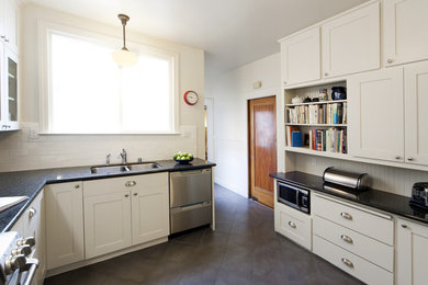 Inspiration for a mid-sized timeless galley light wood floor eat-in kitchen remodel in San Francisco with a drop-in sink, white cabinets, brown backsplash, stainless steel appliances and no island