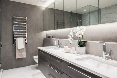 Photo of a large transitional master bathroom in Vancouver with flat-panel cabinets, dark wood cabinets, a corner shower, a wall-mount toilet, brown tile, porcelain tile, brown walls, porcelain floors, an undermount sink, quartzite benchtops, white floor, a hinged shower door, white benchtops, a double vanity and a floating vanity.