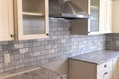 Kitchen - mid-sized contemporary brown floor kitchen idea in Grand Rapids with a drop-in sink, gray backsplash, brick backsplash, stainless steel appliances and an island