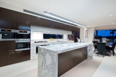 Large contemporary single-wall eat-in kitchen in Brisbane with an undermount sink, flat-panel cabinets, dark wood cabinets, marble benchtops, white splashback, stainless steel appliances, ceramic floors and with island.