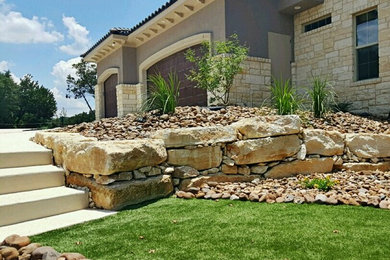 Photo of a large rustic full sun backyard retaining wall landscape in Austin.