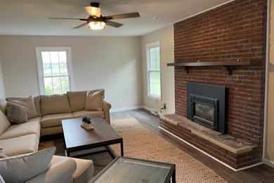 ルイビルにある広いトラディショナルスタイルのおしゃれな独立型リビング (ベージュの壁、無垢フローリング、標準型暖炉、レンガの暖炉まわり、茶色い床) の写真