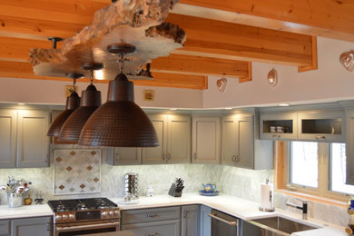Kitchen - large transitional l-shaped kitchen idea in Little Rock with a farmhouse sink, quartz countertops, marble backsplash, stainless steel appliances, an island, recessed-panel cabinets, gray cabinets, gray backsplash and white countertops