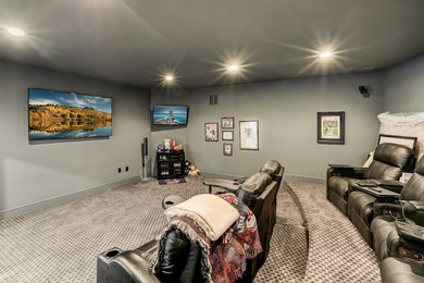 Photo of a large transitional enclosed home theatre in New York with grey walls, carpet, a wall-mounted tv and grey floor.