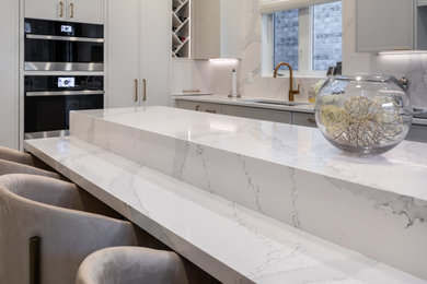 Inspiration for a large u-shaped kitchen in Toronto with a submerged sink, white cabinets, engineered stone countertops, white splashback, engineered quartz splashback, integrated appliances, porcelain flooring, an island, grey floors and white worktops.