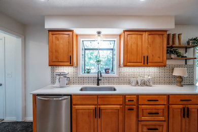 Example of a large 1950s galley vinyl floor and beige floor eat-in kitchen design in Portland with an undermount sink, raised-panel cabinets, medium tone wood cabinets, quartz countertops, multicolored backsplash, ceramic backsplash, stainless steel appliances, an island and white countertops