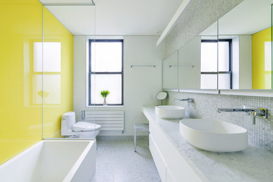 Example of a trendy multicolored tile mosaic tile floor bathroom design in New York with flat-panel cabinets, white cabinets, a one-piece toilet, yellow walls, a vessel sink and marble countertops