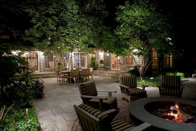 Example of a large tuscan backyard stone patio design in Chicago with a fire pit and a pergola