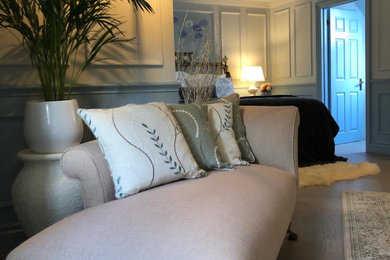 Diseño de dormitorio principal clásico grande con paredes azules, suelo de madera en tonos medios y panelado