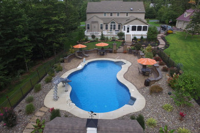 Design ideas for a large backyard custom-shaped pool in Philadelphia with concrete pavers.