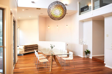 Photo of a large modern dining room in Sydney with grey walls, laminate floors and brown floor.