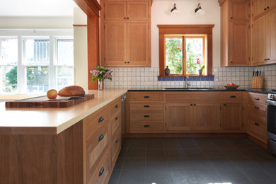 Eat-in kitchen - large craftsman u-shaped slate floor and gray floor eat-in kitchen idea in Seattle with an undermount sink, recessed-panel cabinets, medium tone wood cabinets, soapstone countertops, white backsplash, ceramic backsplash, stainless steel appliances, no island and black countertops