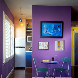 Cette image montre une petite salle à manger ouverte sur la cuisine design avec un mur violet, un sol en bois brun et un sol marron.