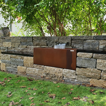Natursteinmauer mit Wasserspiel und Sitzgelegenheiten