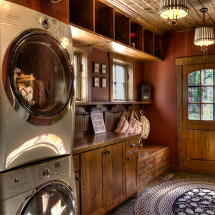 Design ideas for a medium sized rustic utility room in Minneapolis with red walls and a stacked washer and dryer.