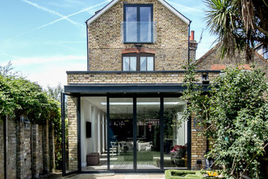 Photo of a medium sized and brown contemporary brick and rear house exterior in Surrey with three floors and a pitched roof.